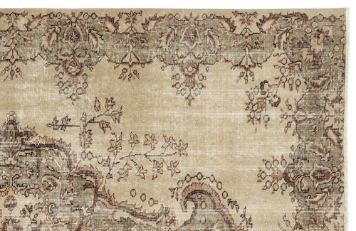Load image 1 in gallery view. A close-up of the Clera Vintage Medallion Rug (5'7" x 8'10") in beige, showcasing green vintage accents, an intricate floral and scroll border, and a center with faded decorative details.