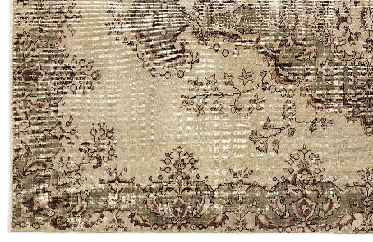 A section of the Clera - Vintage Medallion Rug (5'7 X 8'10) displays an ornate floral pattern with green and brown on beige, bordered by symmetrical motifs and intricate designs for a classic Anatolian look.