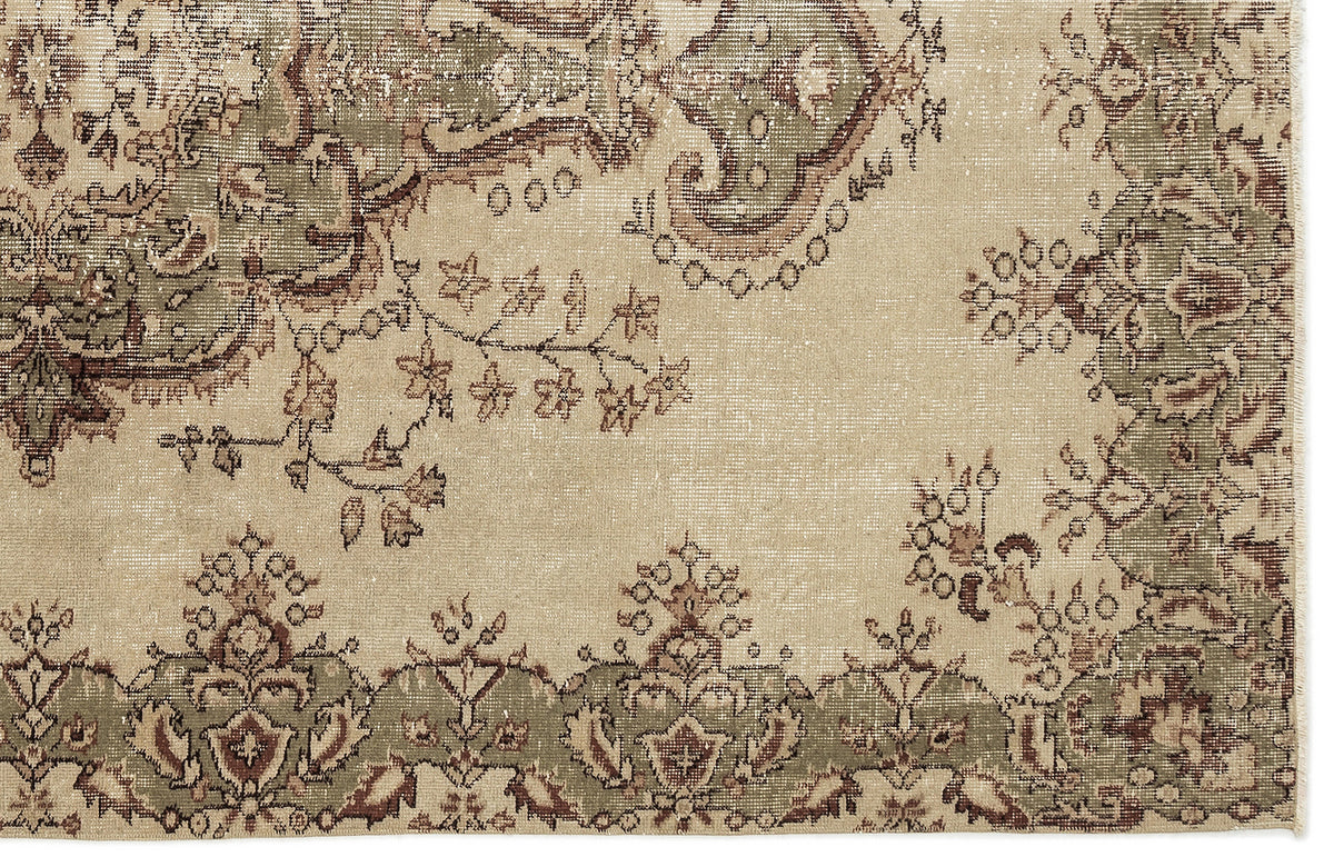 A close-up of the Clera - Vintage Medallion Rug (5'7 x 8'10) highlights its traditional beige design with green and brown floral and vine patterns along the border, showcasing intricate woven details.