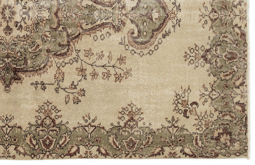 Load image 1 in gallery view. A close-up of the Clera - Vintage Medallion Rug (5'7 x 8'10) highlights its traditional beige design with green and brown floral and vine patterns along the border, showcasing intricate woven details.