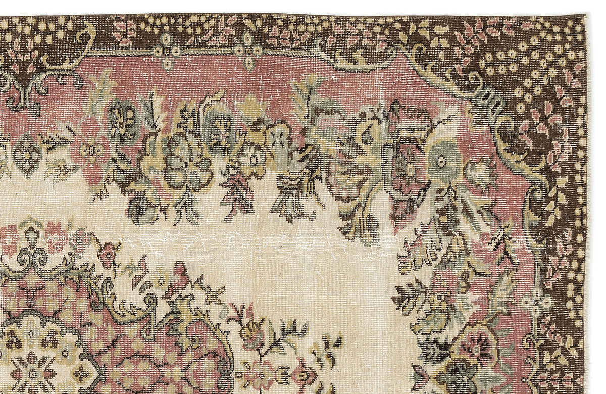 Distressed vintage-style rug with a floral medallion pattern in muted pink, sage green, and brown on a cream background.