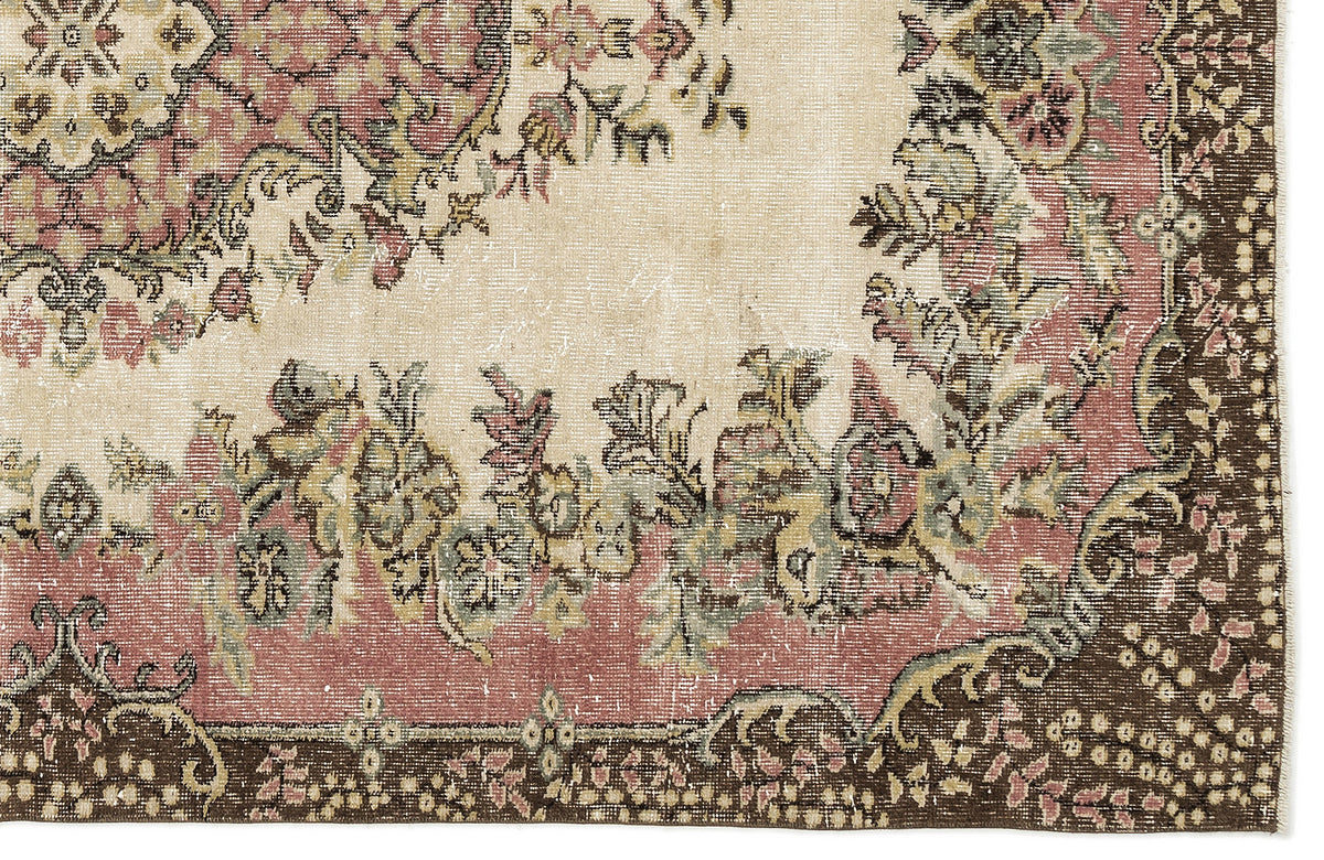 Distressed cream, pink, and brown rug with a traditional floral medallion pattern and ornate border.