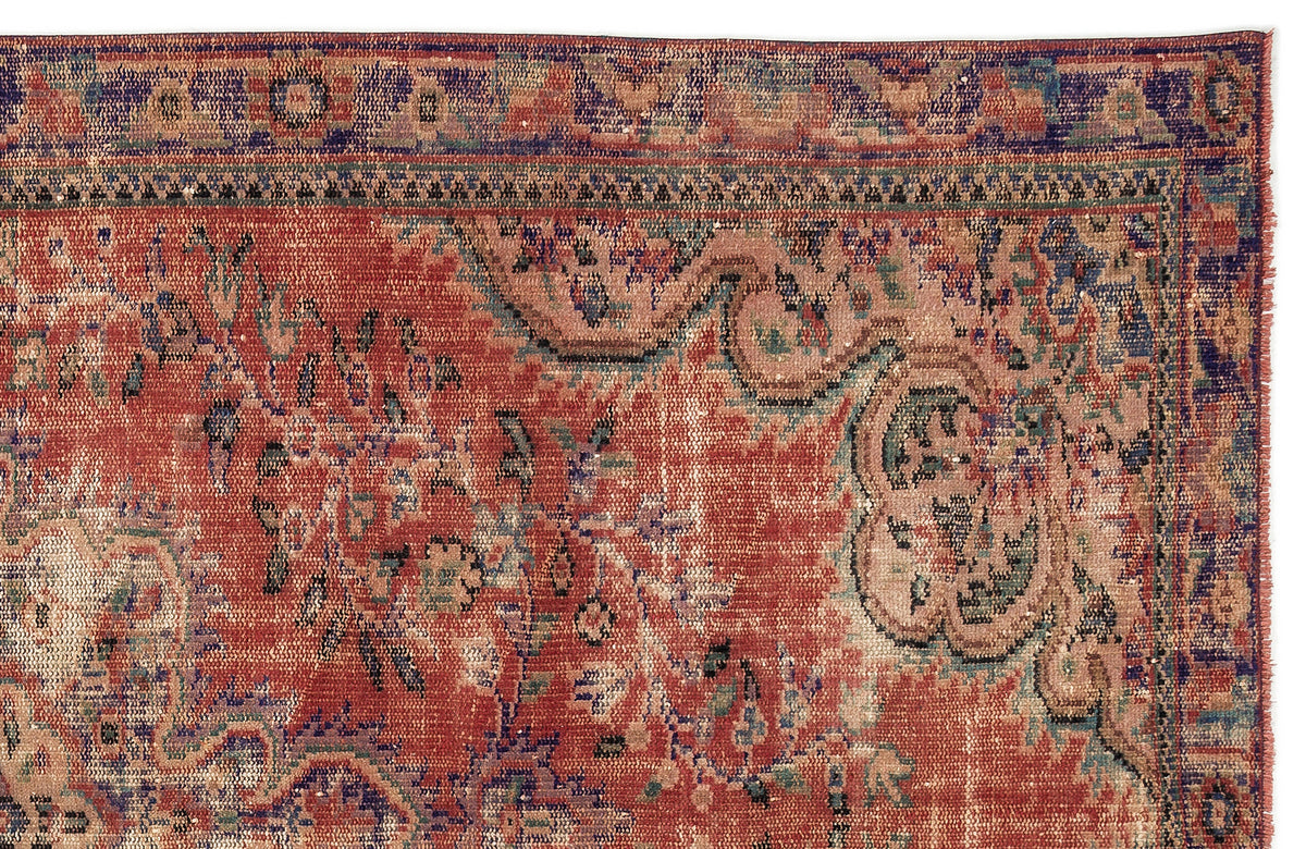 Distressed terracotta, blue, and beige rug with a traditional floral medallion pattern and a fringed edge.