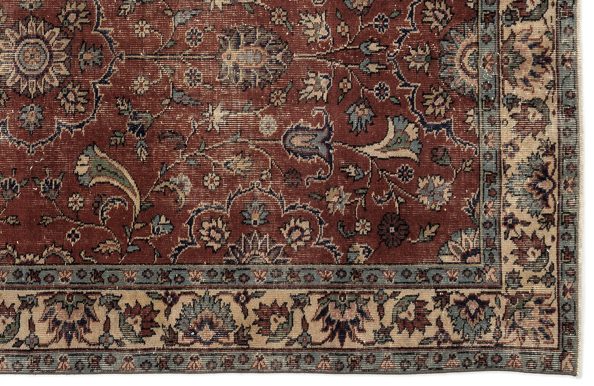 Traditional Persian-style rug with a deep red field, intricate floral vine patterns, and a beige and blue border.