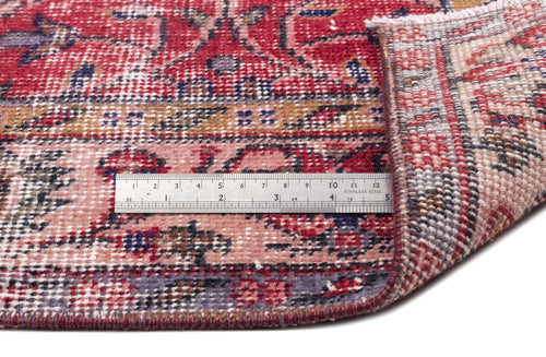 Load image 1 in gallery view. Red, pink, and blue traditional patterned rug with a folded corner and a metal ruler for scale on a white background.