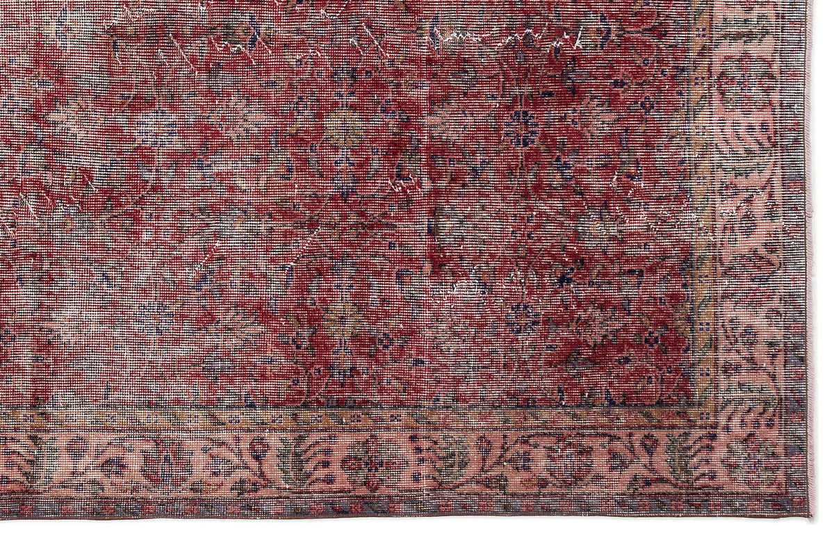 Distressed red and pink traditional rug with a faded floral medallion pattern and a detailed border.