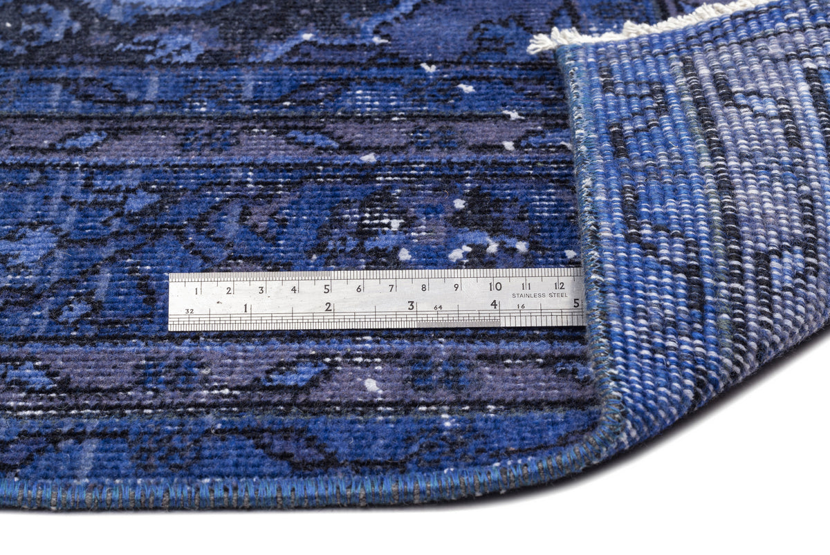 Blue and black distressed patterned rug with a white fringe, shown with a metal ruler for scale.