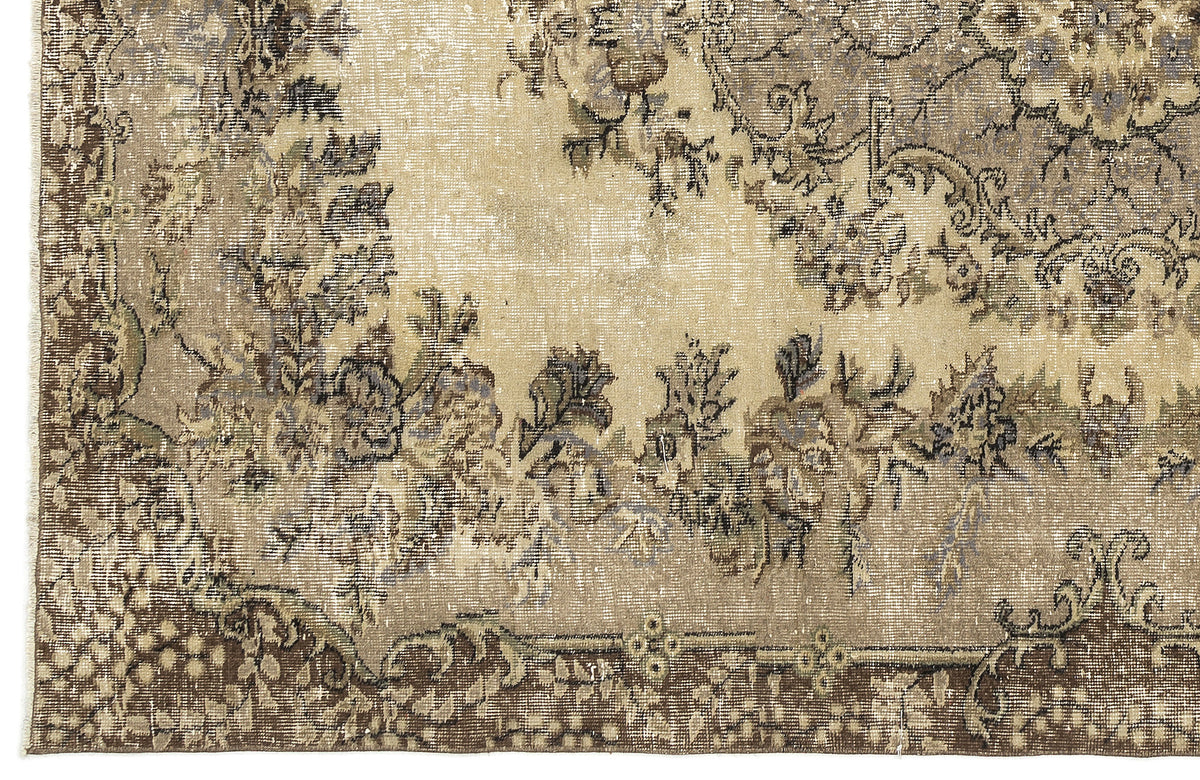Beige and brown distressed rug with a faded floral medallion pattern and a detailed border.