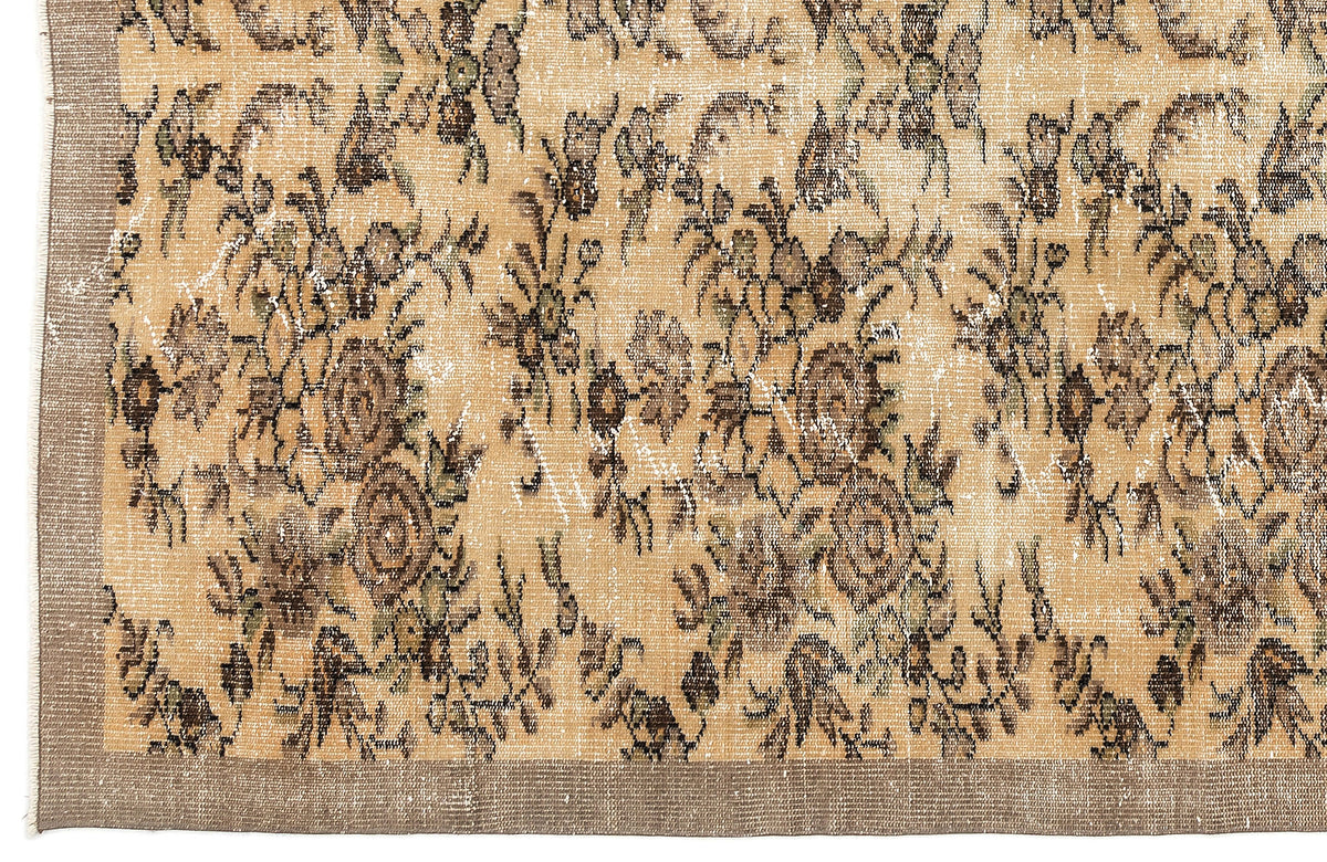 Tan and brown distressed rug with a faded floral pattern and a solid border.