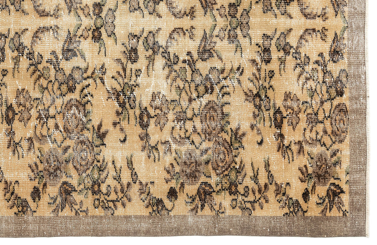 Tan and brown distressed rug with a faded floral pattern and a solid border.