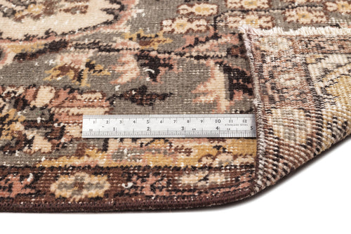 Load image 1 in gallery view. Distressed floral medallion rug in grey, brown, and cream with a metal ruler showing scale and a folded corner.