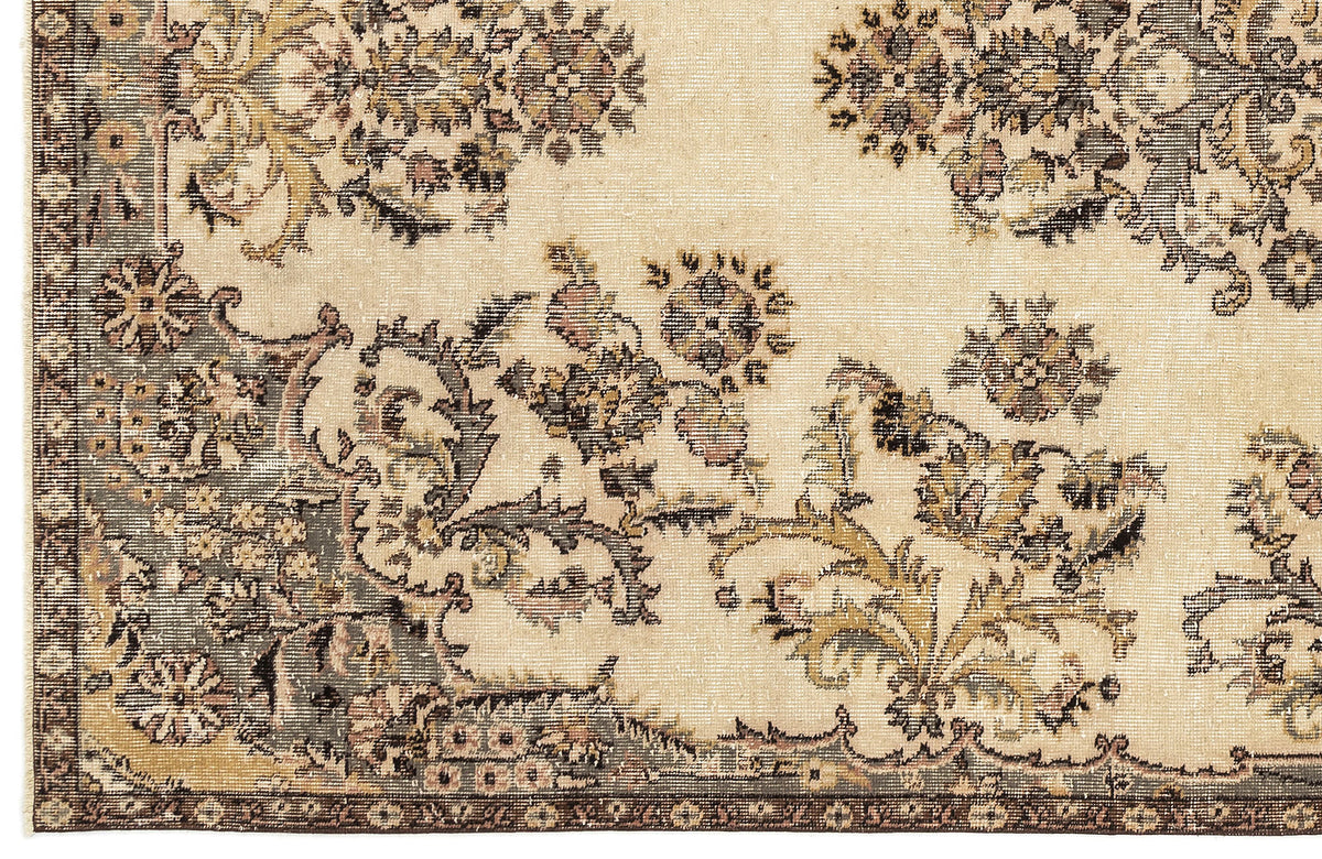 Beige rug with a distressed floral medallion pattern in muted charcoal, olive, and dusty rose tones.