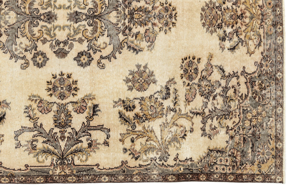 Beige rug with a distressed, dark brown and muted green floral medallion pattern and a decorative border.