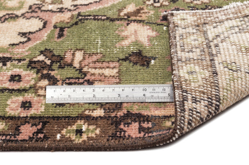 Load image 1 in gallery view. Olive green, pink, and brown floral patterned rug with a folded corner revealing the woven backing and a metal ruler.