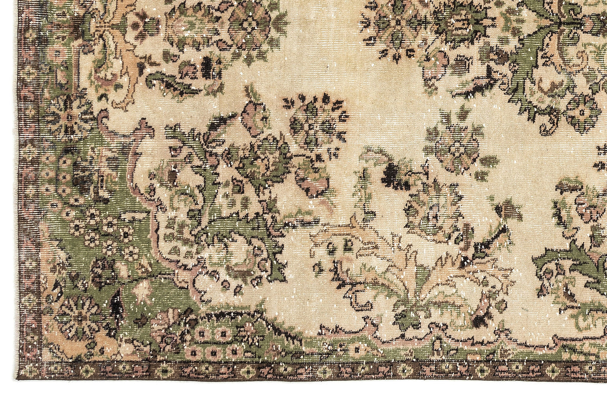 Beige, green, and brown vintage-style rug with a distressed floral medallion pattern and a dark border.