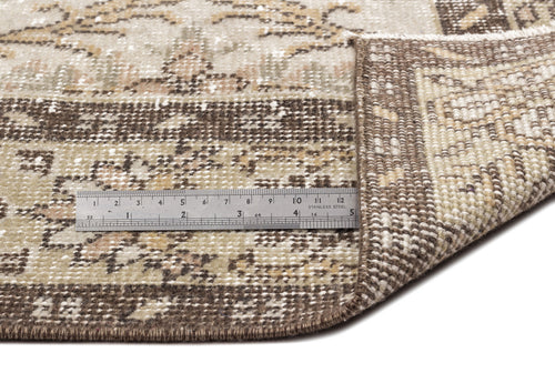 Load image 1 in gallery view. A close-up of the Sadeane - Vintage Floral Rug (6'0 x 9'8) shows its flatwoven corner folded to reveal the underside, with a metal ruler beside it displaying inch and centimeter measurements for scale.