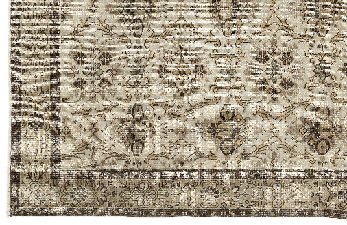 A close-up of the Sadeane Vintage Floral Rug (6'0 x 9'8) showcasing its ornate beige, brown, and taupe floral and geometric patterns with a decorative border along the left and bottom edges.