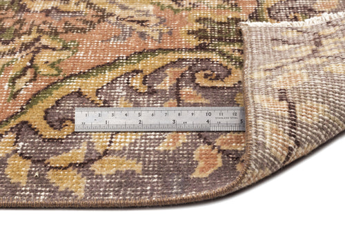 Load image 1 in gallery view. Distressed brown, tan, and green floral medallion rug with a folded corner and a metal ruler for scale on white background.