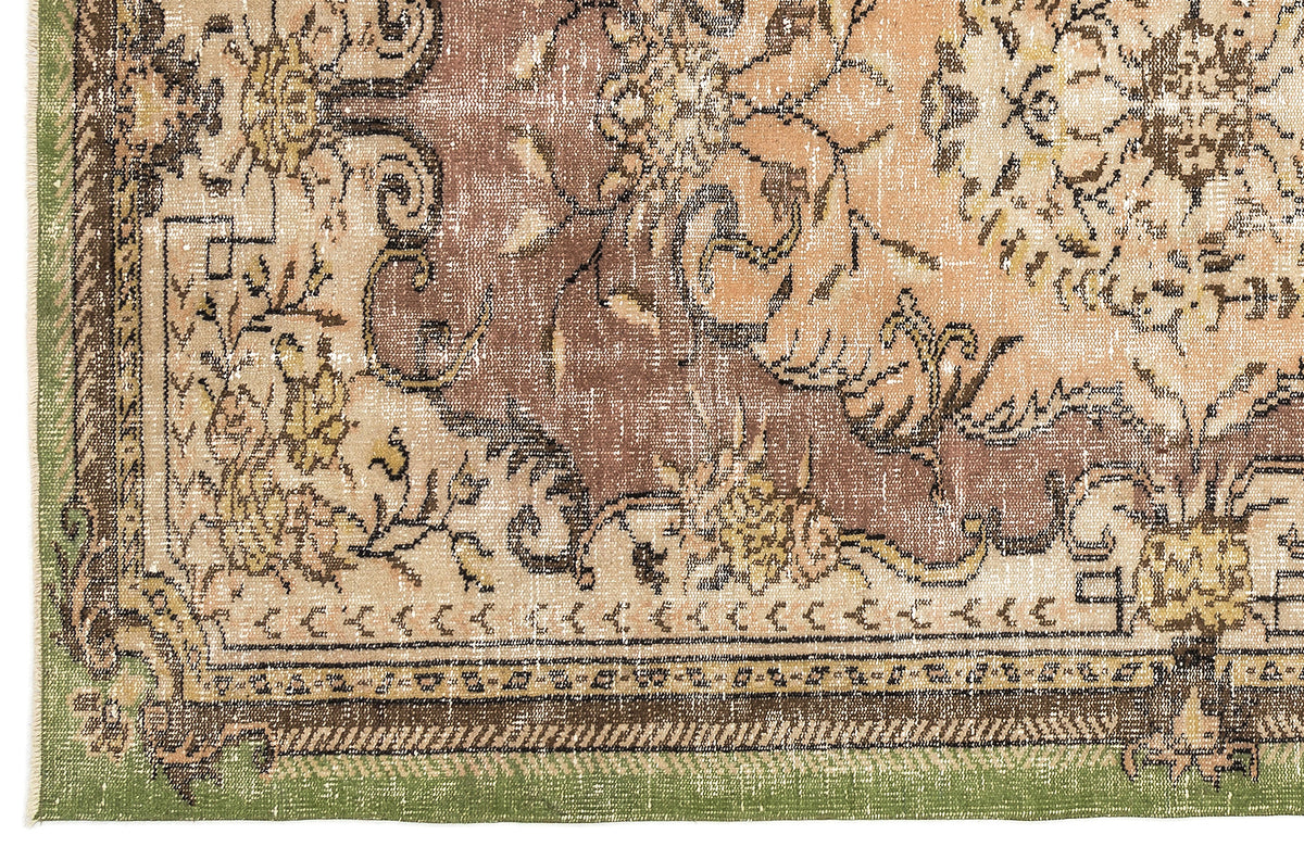 Distressed brown, beige, and green vintage-style rug with an ornate floral medallion pattern and a decorative border.