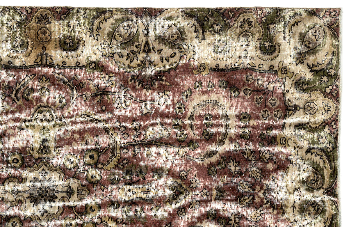 Distressed terracotta, sage green, and cream rug with a traditional floral medallion and paisley border pattern.