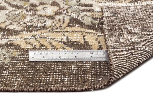 Load image 1 in gallery view. Brown and beige vintage-style rug with a floral pattern, showing the underside and a metal ruler for scale.