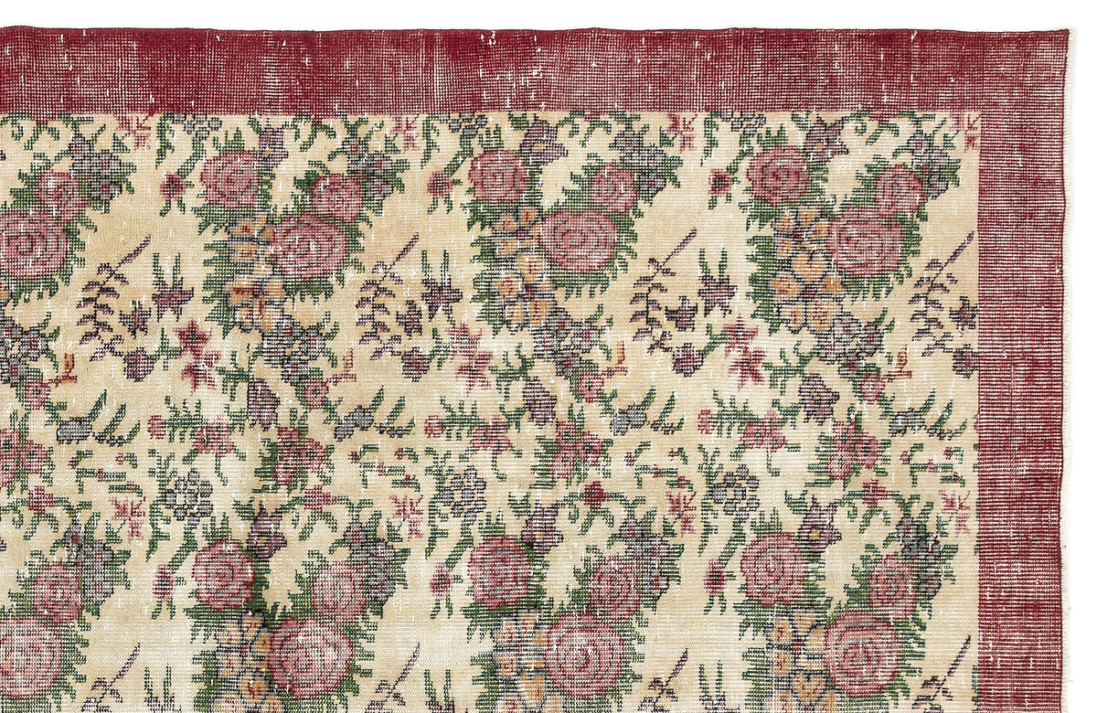 Distressed cream rug with a red border and a repeating floral pattern in shades of red, green, and dark grey.