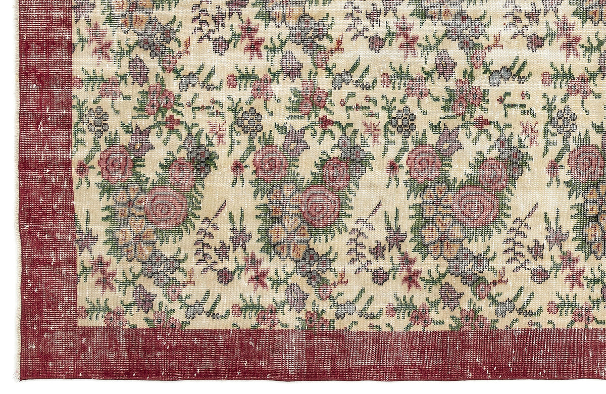 Cream rug with a distressed floral pattern in red, green, and grey, featuring a solid red border.