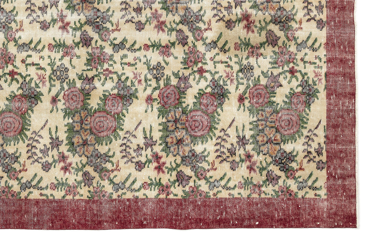Cream rug with a distressed floral pattern in red, green, and purple, featuring a solid red border.