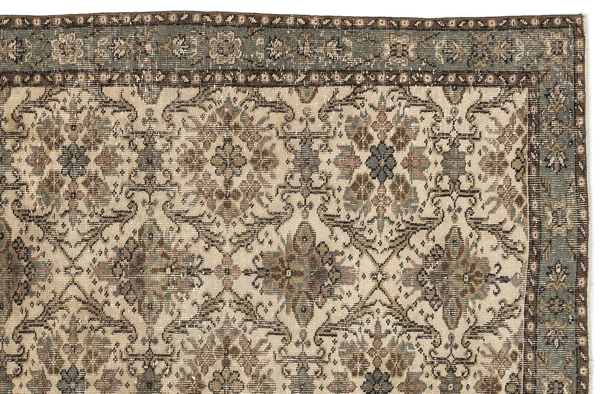 Distressed beige rug with a repeating floral medallion pattern in muted blue, brown, and grey on a white background.