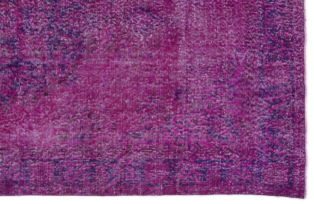 Magenta and deep purple distressed vintage-style rug with a faded traditional floral medallion pattern.