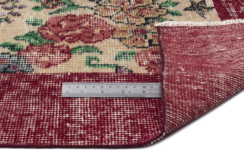 Load image 1 in gallery view. Beige and red floral rug with a folded corner revealing the underside, shown with a metal ruler for scale.