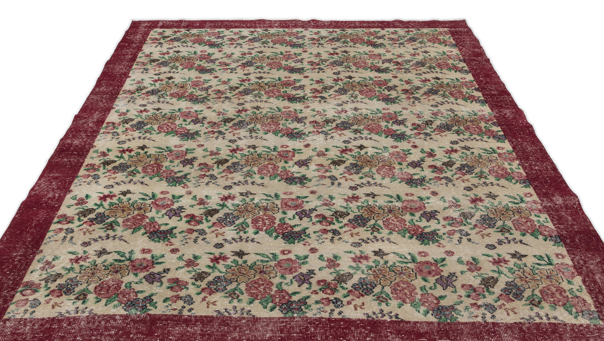 Beige rug with a distressed floral pattern in red, green, and purple, featuring a wide solid red border.