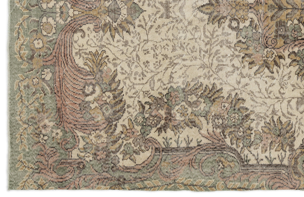Distressed traditional rug with a floral medallion pattern in muted sage green, dusty rose, and beige tones.
