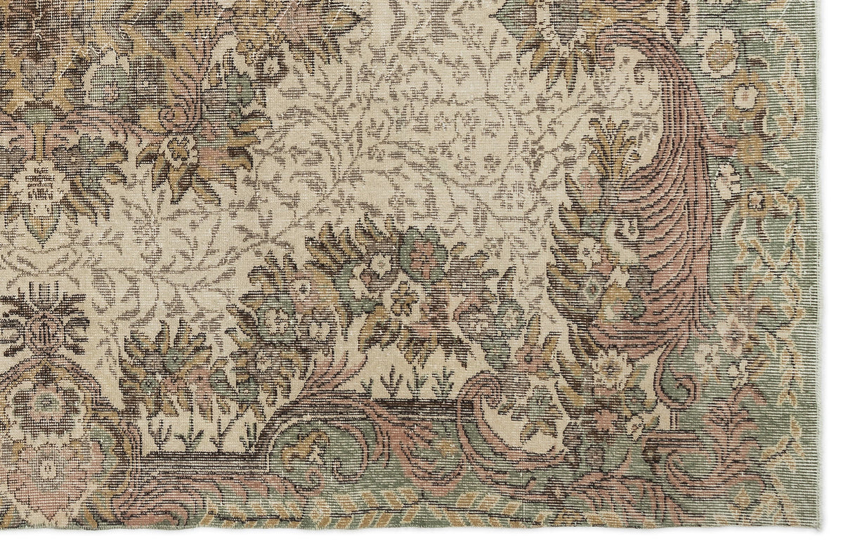 Beige rug with a distressed traditional floral and vine pattern in muted sage green, dusty rose, and brown.