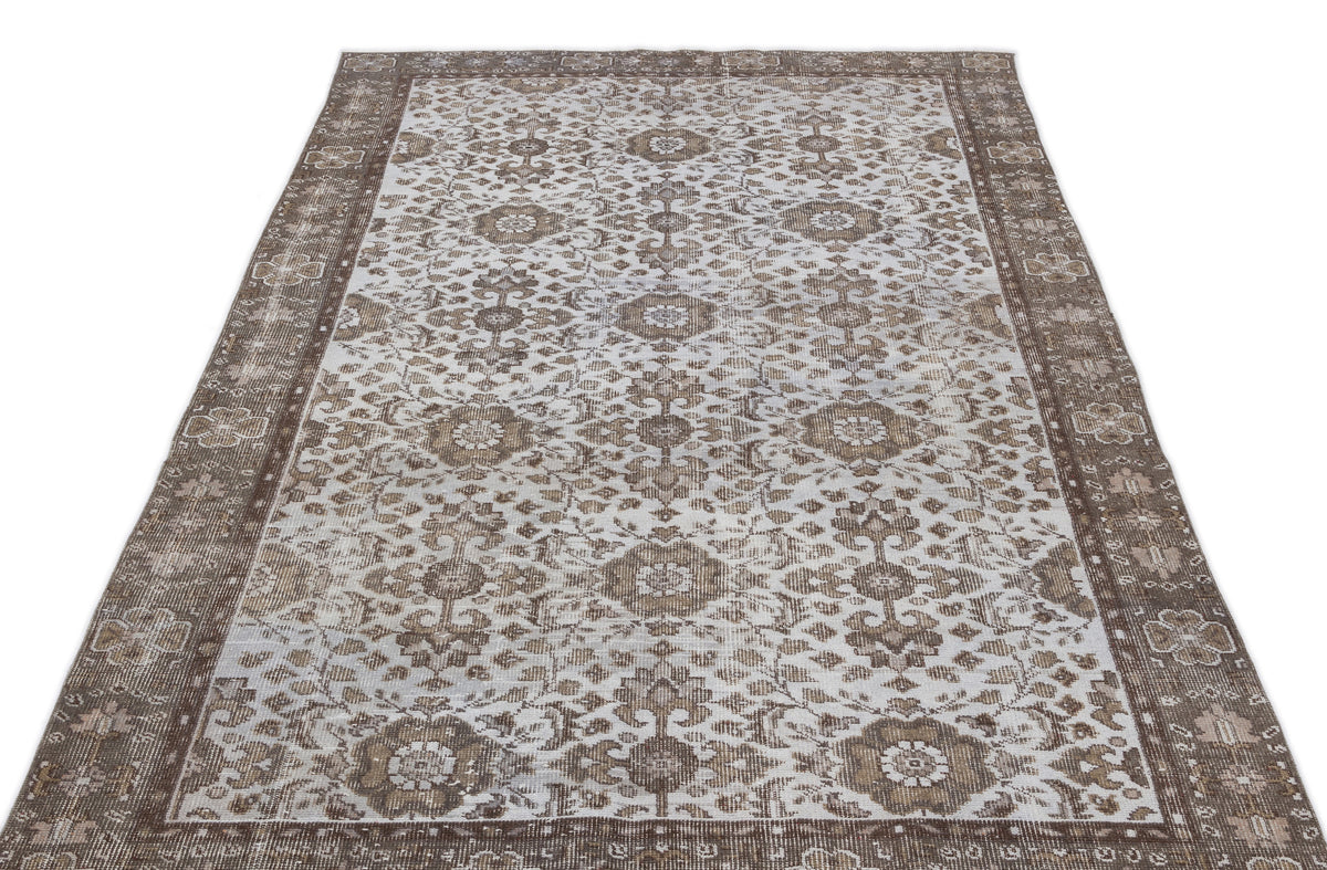Brown and cream vintage-style rug with a distressed floral medallion pattern and a wide decorative border.