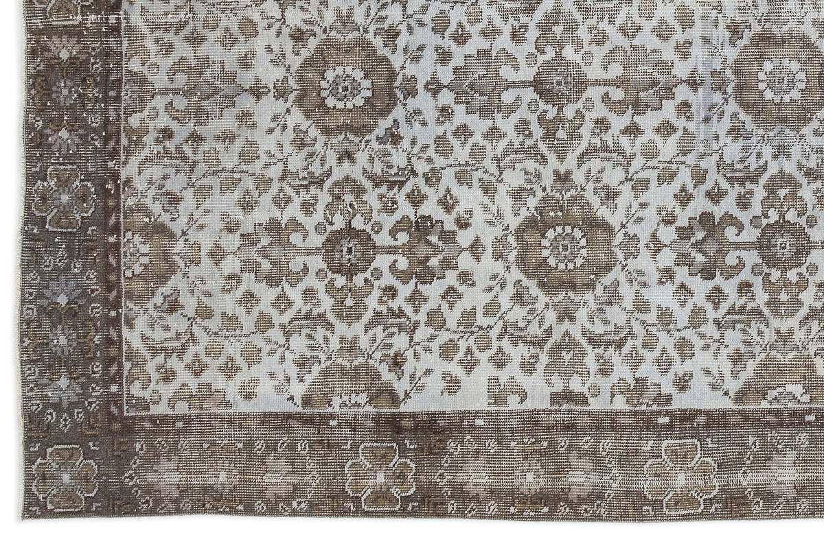 Distressed brown and light blue rug with a traditional floral medallion pattern and a wide decorative border.