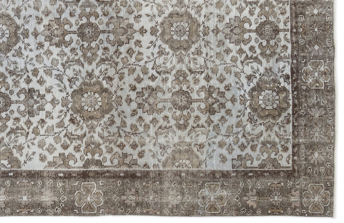 Brown and cream distressed rug with a traditional floral medallion pattern and a wide decorative border.
