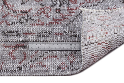 Load image 1 in gallery view. Grey, red, and black distressed floral rug with a folded corner showing the backing and a metal ruler for scale.