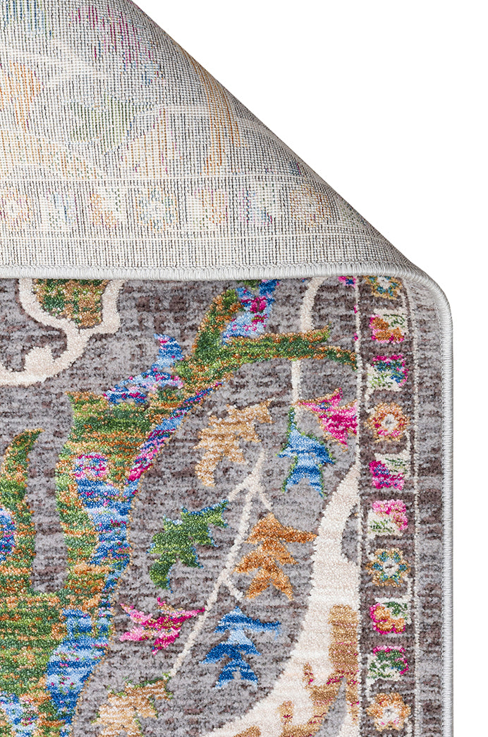 Grey rug with a multi-colored floral medallion pattern and a folded corner showing the woven backing.