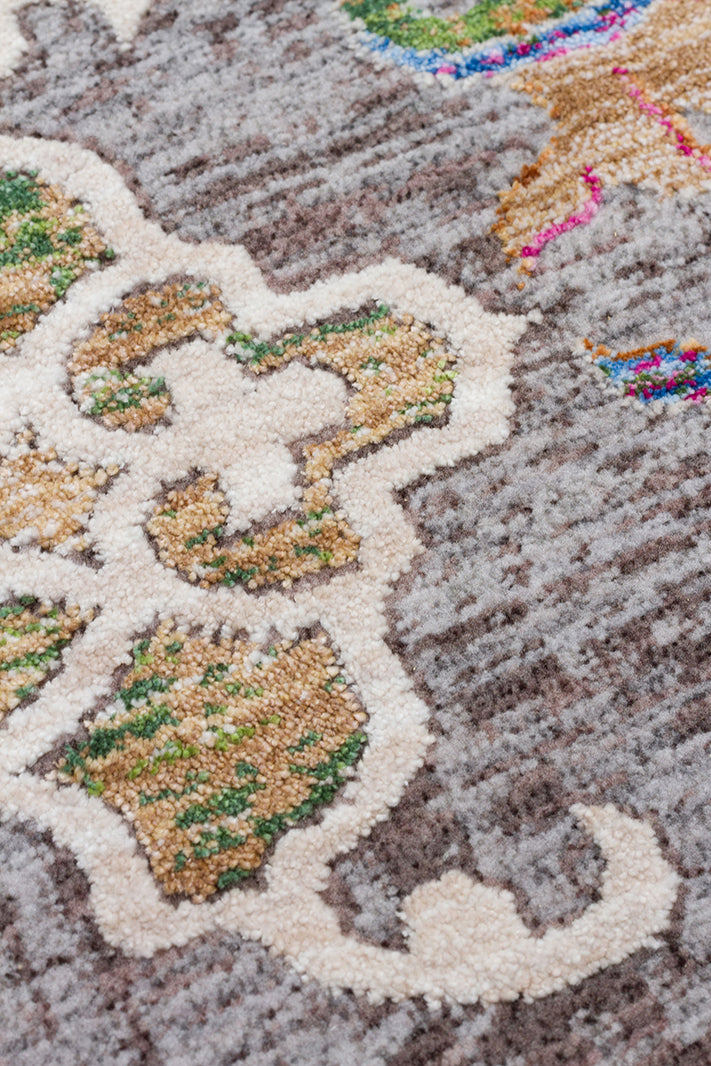 Grey textured rug with cream, tan, and green floral medallion patterns and small accents of bright pink and blue.