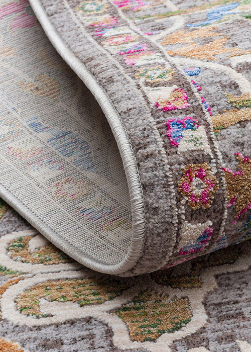 Load image 1 in gallery view. Grey traditional rug with a folded corner revealing a multi-colored floral pattern in pink, blue, and gold.
