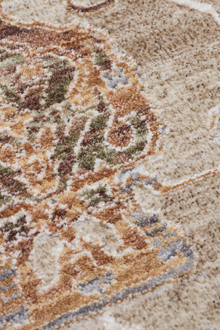 Close-up of a traditional rug with a beige field and a detailed medallion pattern in rust, olive green, and slate blue.
