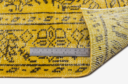 Load image 1 in gallery view. Mustard yellow and dark brown rug with a traditional floral pattern, shown with a metal ruler for scale.