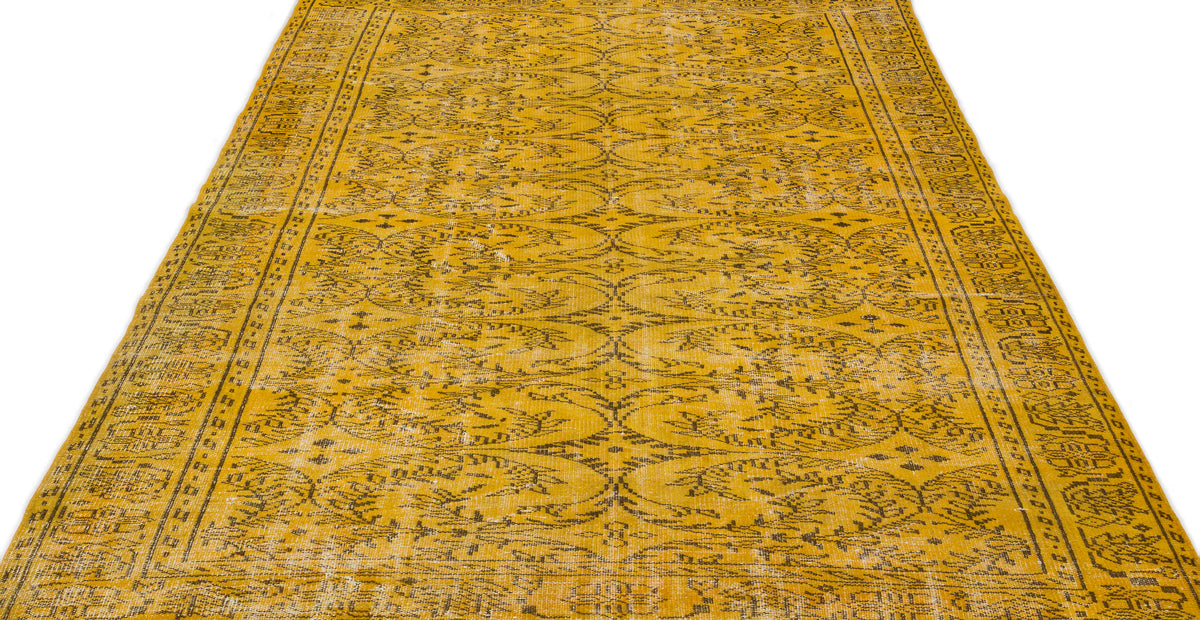 Mustard yellow rug with a distressed black floral medallion pattern and a decorative border.