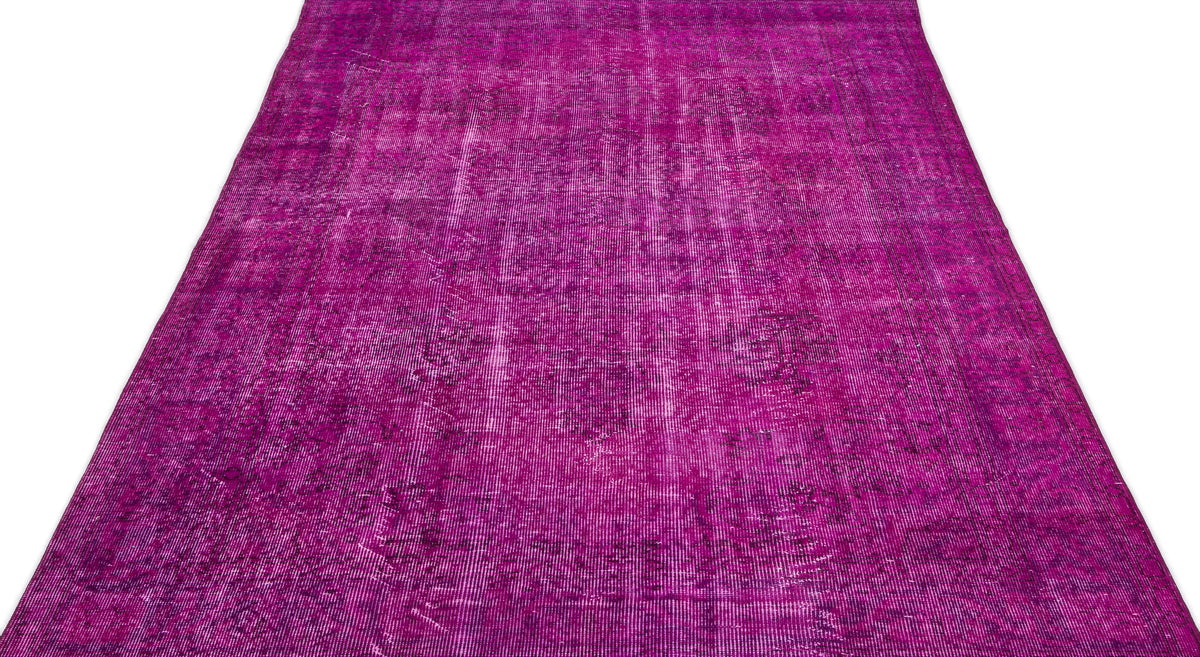 Magenta overdyed vintage-style rug with a faded, distressed traditional pattern.