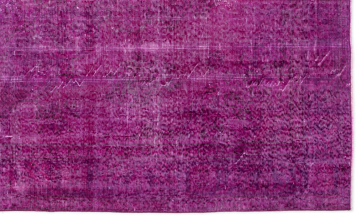 Magenta rug with a distressed, overdyed vintage pattern and visible woven texture.