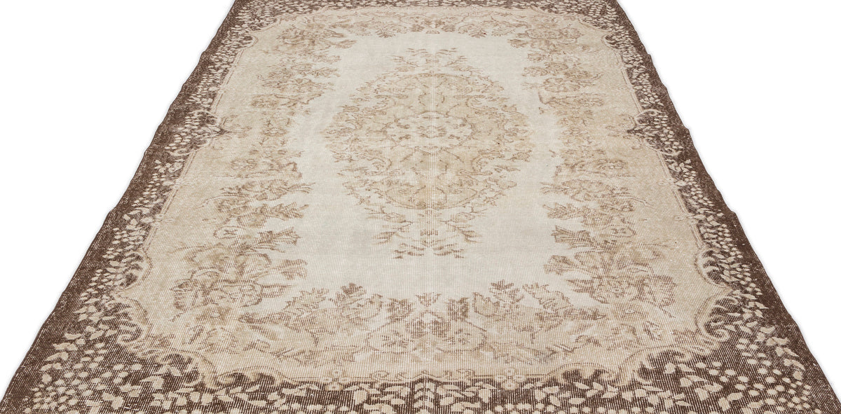 The Pririna Vintage Medallion Rug (6'2" x 9'7") features a long, rectangular shape with ornate beige and brown floral and medallion patterns, faded detailing, and a decorative border.