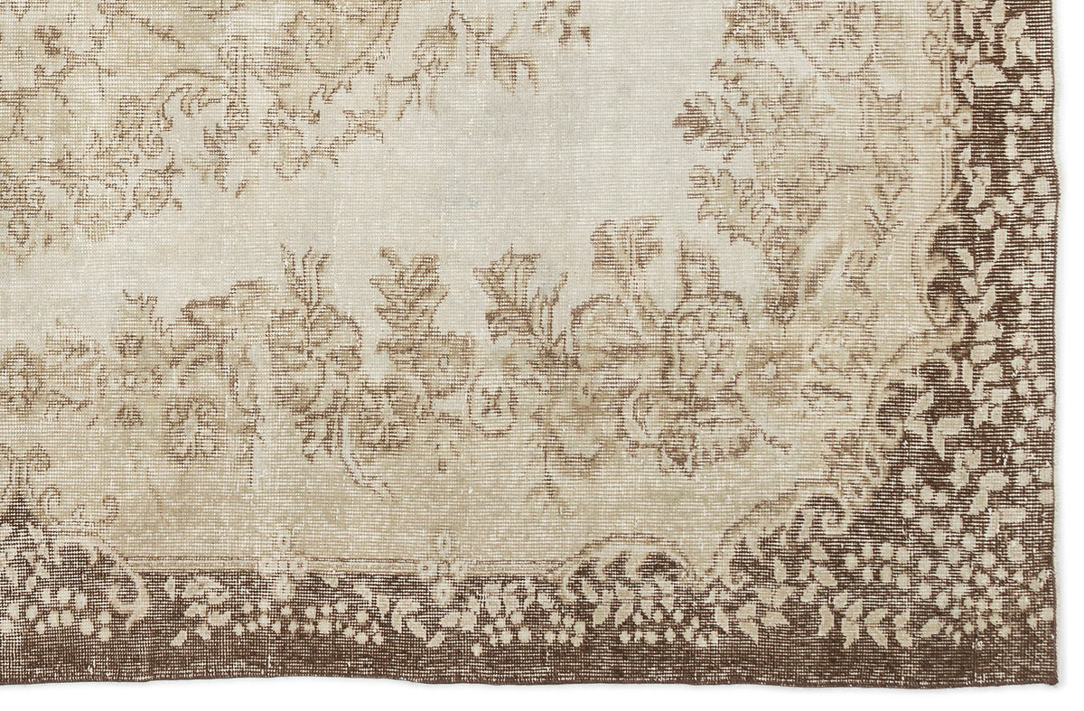 A section of the Pririna - Vintage Medallion Rug (6'2 x 9'7) in beige and brown, featuring a faded floral pattern, decorative border, and detailed woven textures with soft, muted colors.