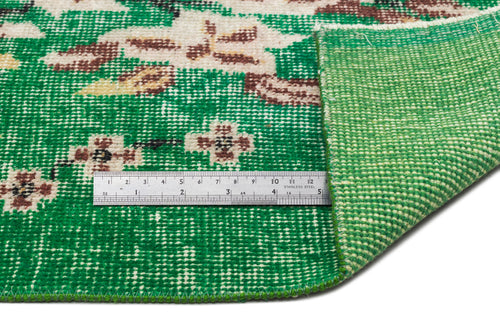 Load image 1 in gallery view. Emerald green rug with a floral medallion pattern in cream and brown, showing the woven backing and a metal ruler.