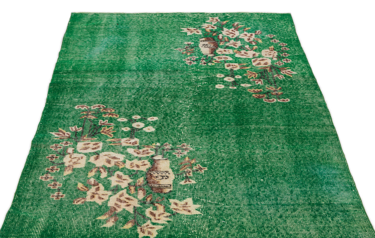 Emerald green distressed rug with white and brown floral vase motifs on a white background.